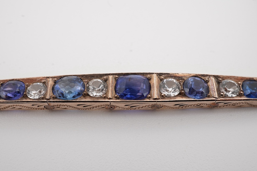 An early 20th century yellow metal and graduated two colour sapphire set line bracelet, with safety chain, gross weight 6.8 grams. Condition - fair